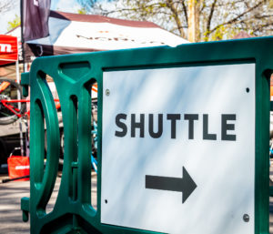 Green event barricade with directional signage ("shuttle") pointing right