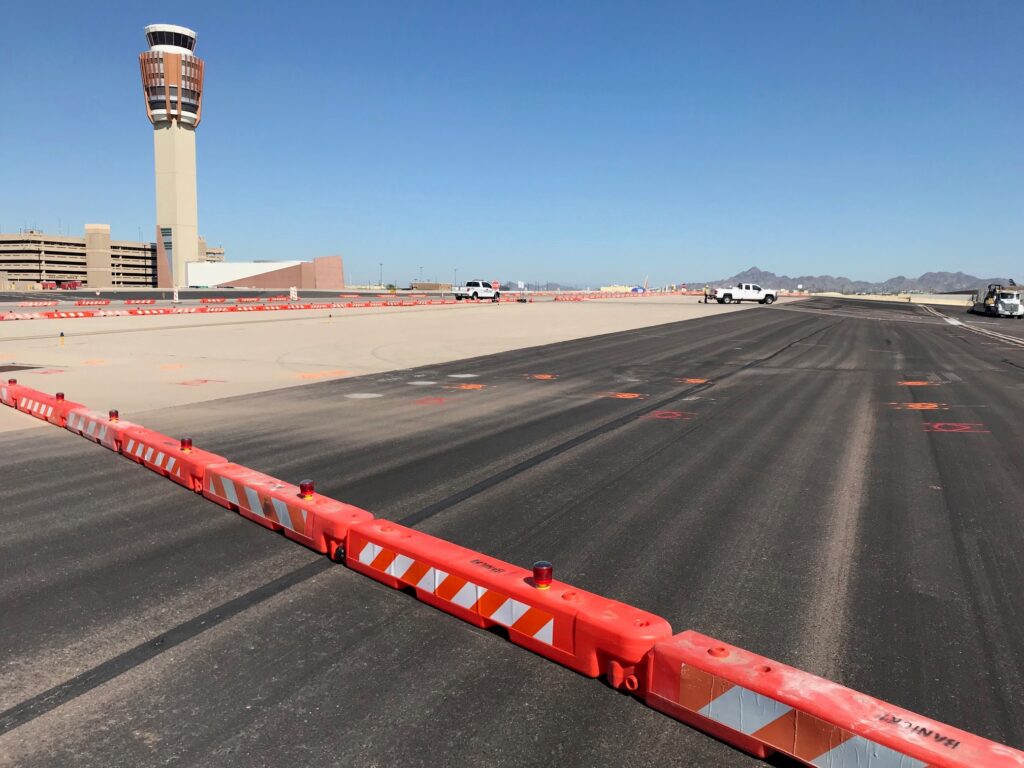 Orange low-profile barriers cross a runway at an airport