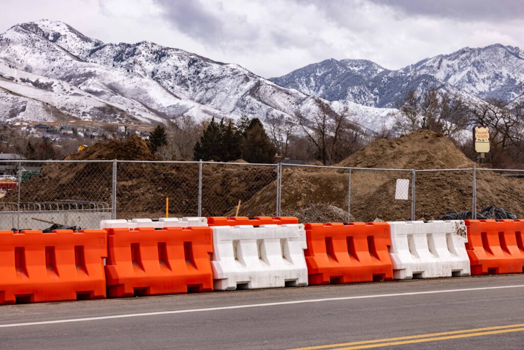 Water filled barrier protecting a road side construction zone. The background of the image shows snow capped hills.