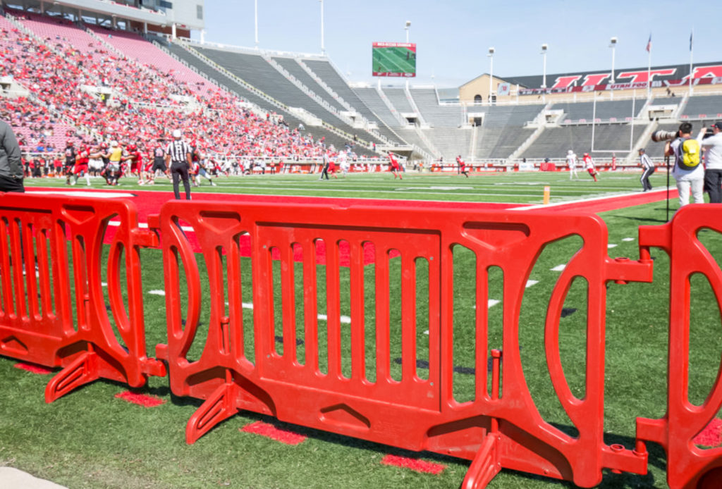 red crowd control barriers lining the football field at Utah St. University