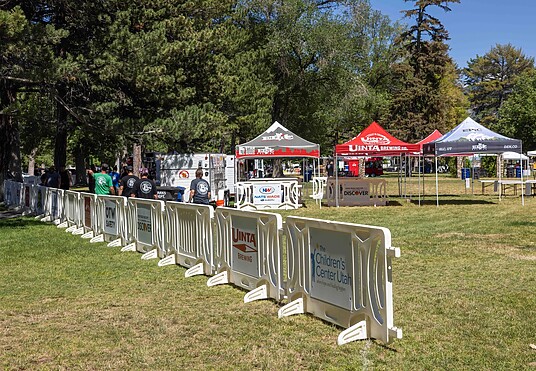 Branded white plastic barricades by OTW Safety at an outdoor food truck festival with vendor tents and attendees