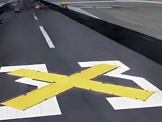 Large yellow vinyl X marker deployed on airport runway for temporary closure