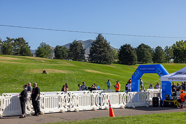 White OTW event barricades line both sides of a path directed toward an inflated arch for the finish line of the 2025 Flutie 5K