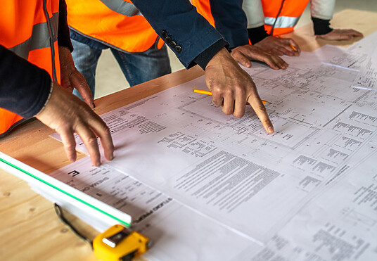 A group of contractors look over plans for a project.
