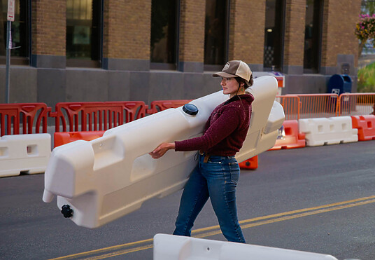 Woman carries OTW low-profile barricade in preparation for Go Karting event